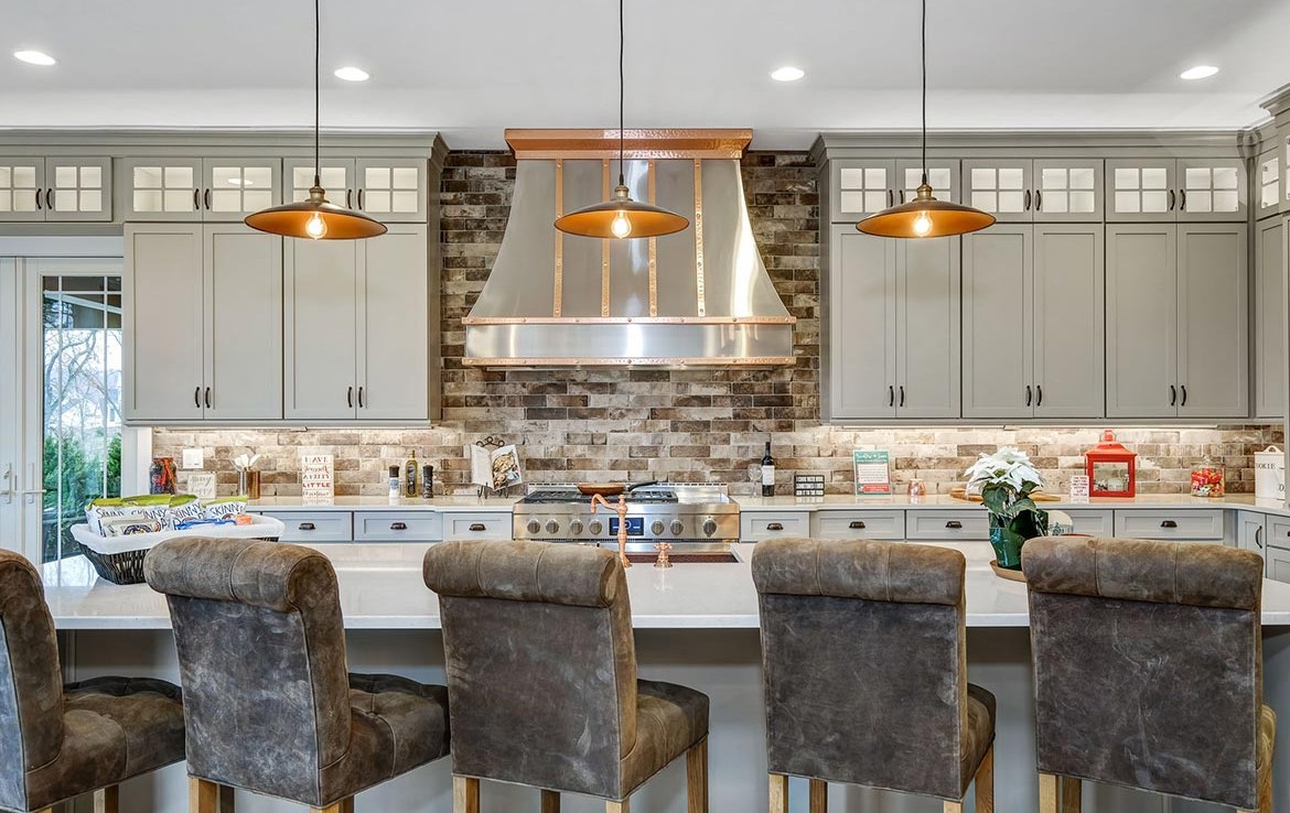 Austin Model Home at Forest Edge, Cranberry, PA, luxury kitchen with gray cabinets, stone backsplash, and copper details – Infinity Custom Homes